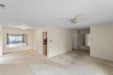 Empty room with light carpet, light tile patterned floors, and ceiling fan
