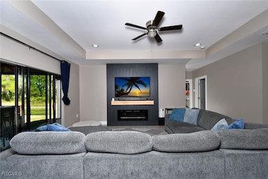 Living room with a fireplace, recessed lighting, a ceiling fan, and a raised ceiling