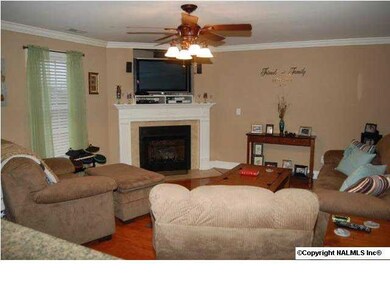 Great room has wood flooring, crown molding, and a gas fireplace.