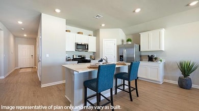 Kitchen featuring light countertops, a breakfast bar, recessed lighting, light wood finished floors, and white cabinets