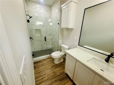 Bathroom with vanity, a marble finish shower, and wood finish floors