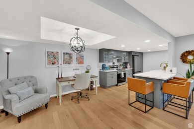 Dining space featuring light wood-type flooring, a chandelier, recessed lighting, a tray ceiling, and a desk