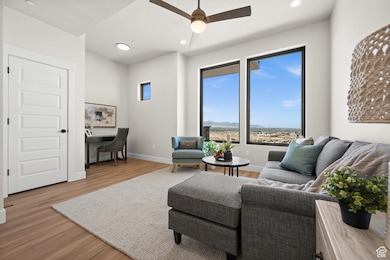 Living area with an office area, light wood-style flooring, recessed lighting, a ceiling fan, and a mountain view