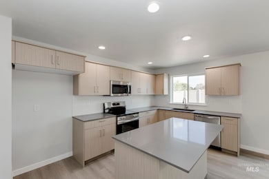 Kitchen with stainless steel appliances, backsplash, light wood-style flooring, light brown cabinets, and recessed lighting