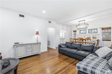 Living room with crown molding, wood finished floors, a chandelier, and recessed lighting