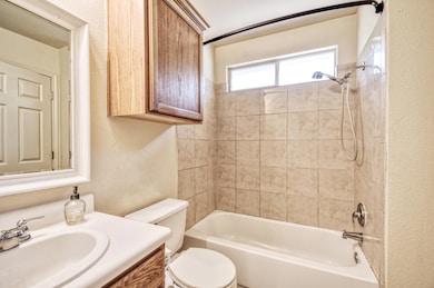 Bathroom featuring a textured wall, vanity, and t