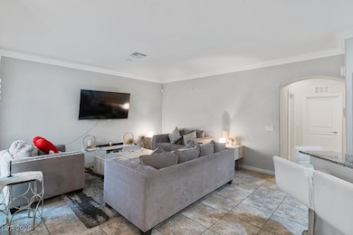 Living area with arched walkways, crown molding, a