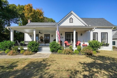 View of front of home featuring covered porch, a front yard, a chimney, and a ceiling fan