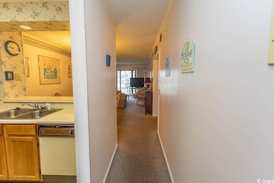 Corridor with a sink, baseboards, wallpapered walls, a textured ceiling, and carpet