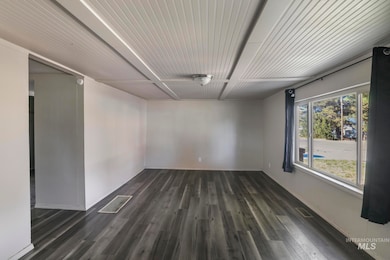 Spare room featuring dark wood-style floors and baseboards