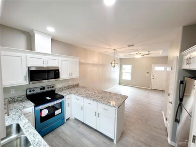 Kitchen featuring appliances with stainless steel finishes, a peninsula, white cabinets, light wood-style flooring, and recessed lighting