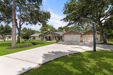 An extra-long paved driveway leads from Falling Leaf Drive amidst the towering trees that dot this property to this charming single-story home with ample parking space and a brick elevation with wood shutters and the most inviting gabled front porch.