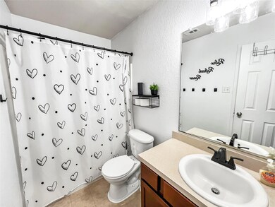 Bathroom with toilet, a textured wall, vanity, a 