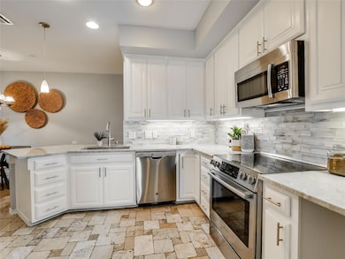 Kitchen with a sink, white cabinets, appliances w