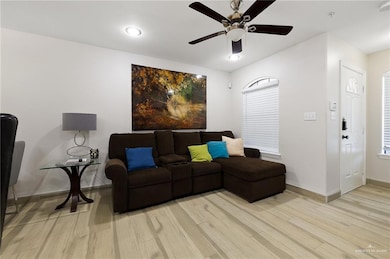 Living area featuring light wood-type flooring, baseboards, and a ceiling fan