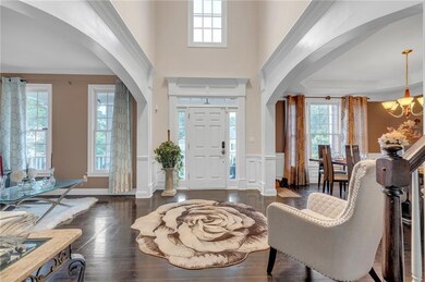 Entryway featuring arched walkways, healthy amount of natural light, a chandelier, ornamental molding, and wainscoting