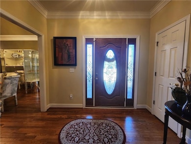 Entrance foyer with crown molding and dark wood-ty