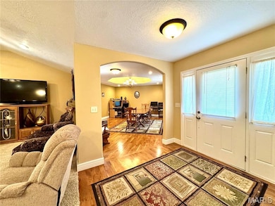 Entryway featuring light wood-style flooring, a textured ceiling, and arched walkways