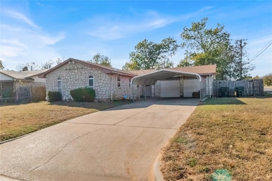 Single story home with concrete driveway, stone siding, and a detached carport