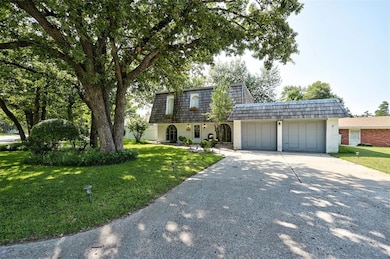 Front of property featuring mansard roof, concrete driveway, a garage, and a front yard