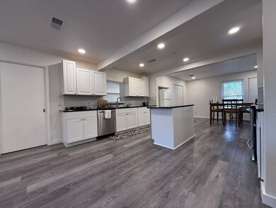 Kitchen featuring white cabinets, dark countertops, dark wood-style flooring, dishwasher, and recessed lighting