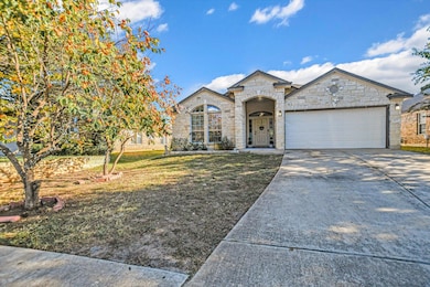 French country inspired facade with stone siding, driveway, a front lawn, and an attached garage