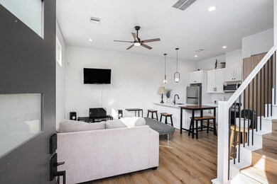 Modern open-concept living area and sleek kitchen featuring stainless steel appliances and breakfast bar.