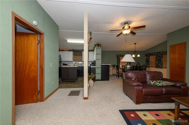 Living room with ceiling fan, a textured ceiling, visible vents, light colored carpet, and lofted ceiling