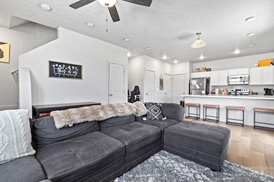 Living room with light wood-style floors, a textured ceiling, and a ceiling fan