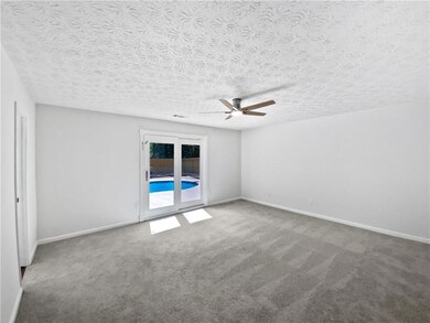 Carpeted empty room with a ceiling fan and a textured ceiling