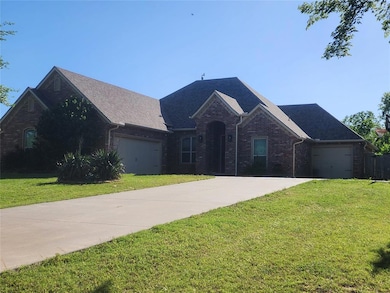 View of front of property featuring concrete driveway, brick siding, a garage, and a front yard