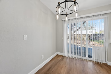 A charming dining area boasts a modern chandelier, elegant wood-look flooring, and sliding glass doors leading to the private backyard.