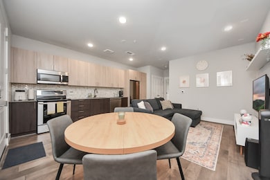 Modern, open-concept living space with a sleek kitchen featuring stainless steel appliances, ample cabinetry, and a stylish backsplash.
