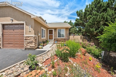 View of front of property with stone siding, stucco siding, an attached garage, and asphalt driveway