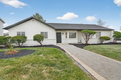 Ranch-style house with a front yard, stucco siding, and roof with shingles