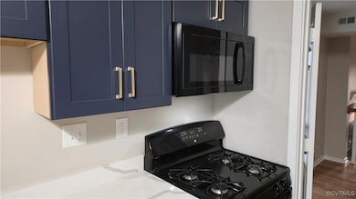 Kitchen with black appliances, blue cabinetry, lig