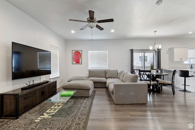 Living room featuring wood finished floors, a chandelier, ceiling fan, and recessed lighting