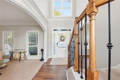 Foyer entrance with arched walkways, a high ceiling, wood finished floors, carpet flooring, and crown molding