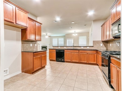 Kitchen featuring black appliances, a sink, a peninsula, tasteful backsplash, and brown cabinets