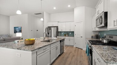 Kitchen with appliances with stainless steel finishes, a sink, white cabinets, decorative backsplash, and light wood-type flooring