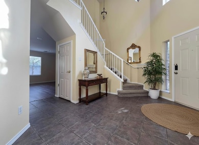 Entrance foyer with dark tile patterned floors, a towering ceiling, and stairs