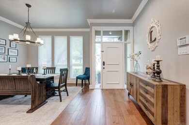 Entrance foyer with hardwood / wood-style floors, a notable chandelier, and crown molding