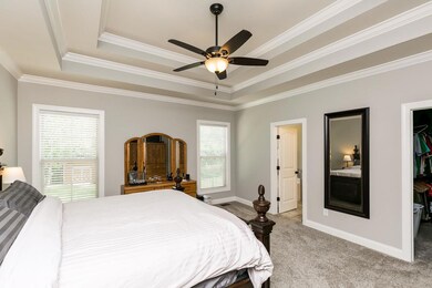 Master bedroom with trey ceilings and ceiling fan.  Windows look out to backyar.d