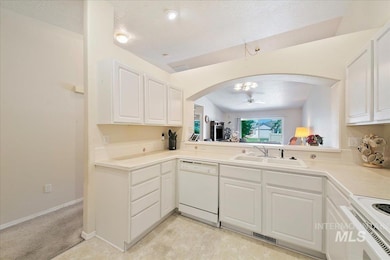 Kitchen with arched walkways, a textured ceiling, white appliances, white cabinetry, and a ceiling fan