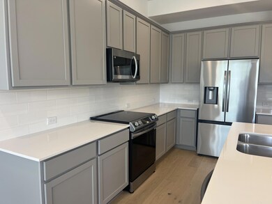 Kitchen featuring gray cabinetry, stainless steel appliances, light wood finished floors, and backsplash