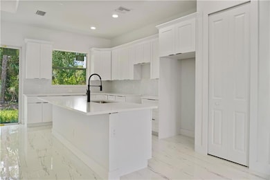 Kitchen featuring decorative backsplash, recessed lighting, light countertops, white cabinetry, and open floor plan