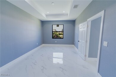 Spare room featuring marble finish floors, a raised ceiling, and recessed lighting