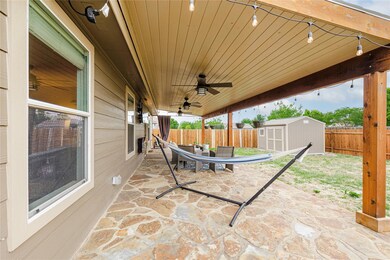 Fenced backyard with a storage unit, a ceiling fan, a patio area, and outdoor dining area