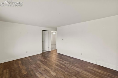 Unfurnished room with dark wood-style flooring and baseboards