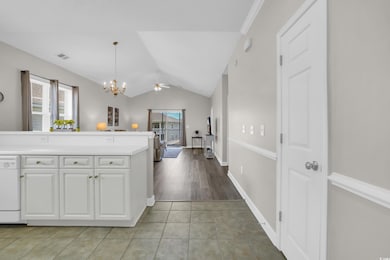 Kitchen featuring plenty of natural light, white dishwasher, white cabinetry, light countertops, and lofted ceiling